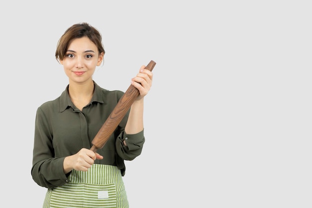 Portrait of pretty woman in apron holding a rolling pin . High quality photo