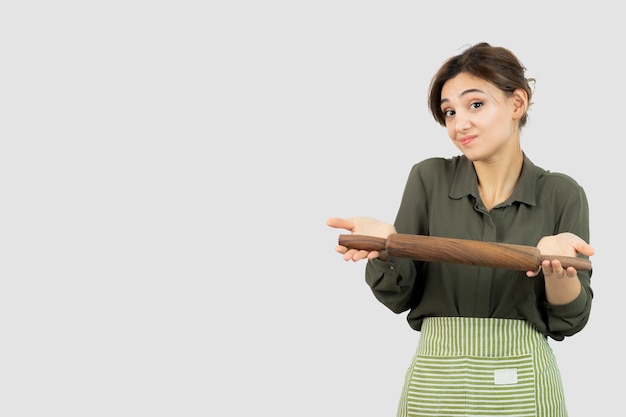 Portrait of pretty woman in apron holding a rolling pin