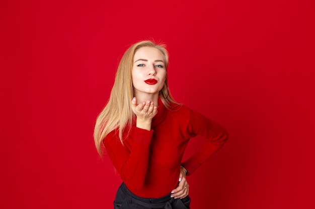 Portrait pretty woman sends air kiss  over red background in the studio- Image 