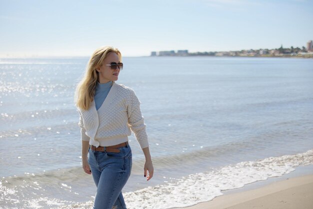 Portrait of a pretty woman walking along the city beach against the backdrop of a sea