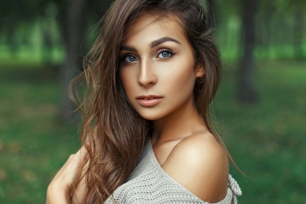 Portrait of a pretty woman with amazing blue eyes with the hairstyle in the park.