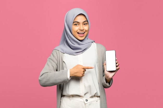 Portrait of pretty young Asian woman pointing joyfully on smartphone with her finger