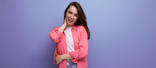 Portrait of a pretty young blackhaired woman in a pink shirt with a hollywood smile on a studio