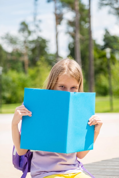 Portrait of a pretty young girl hiding behind an open book