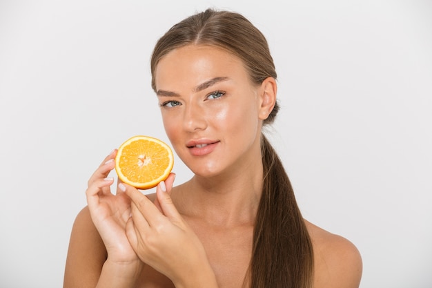 Portrait of a pretty young topless woman isolated, showing sliced orange