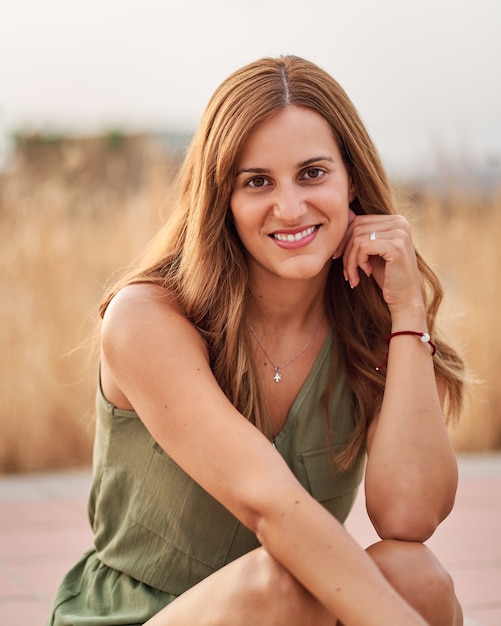 Portrait of a pretty young woman sitting on the sidewalk on the street with a nice out of focus background.