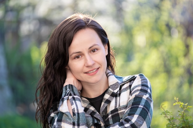 Portrait of pretty young woman smiling happily relaxing outdoors on spring sunny day.