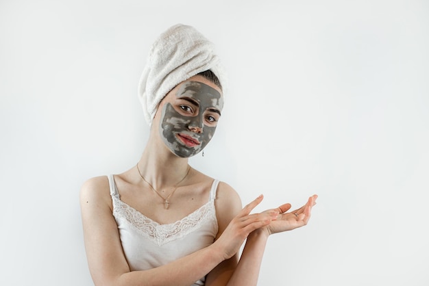 Portrait of pretty young woman wears beauty black clay mask on face isolated on white