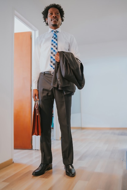 Portrait of professional businessman holding a briefcase while standing at modern office. Business concept.