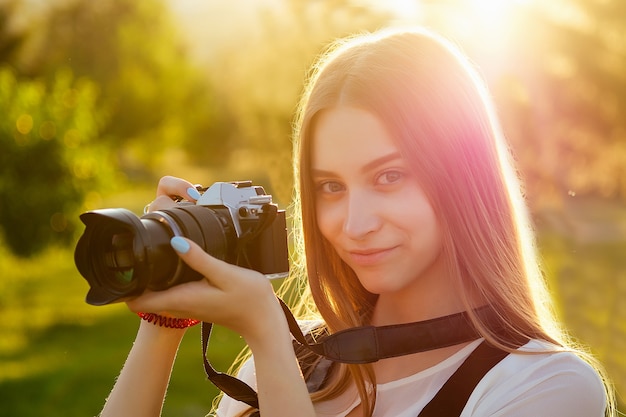 Portrait of professional woman photographer in the park photographing on a camera . photo shoot photosession in the city