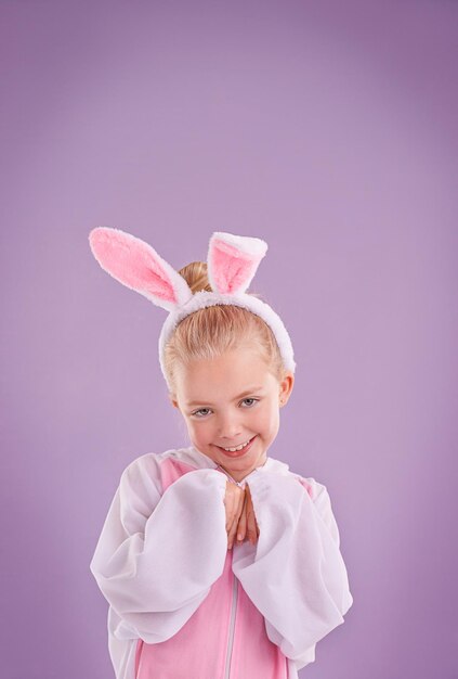 Photo portrait rabbit and girl with costume happiness and halloween outfit on a purple studio background face kid and model with bunny clothes and character with smile and easter holiday with culture