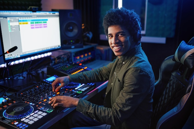 Portrait of radio host using sound mixer in studio