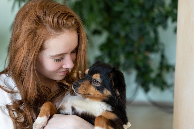 Portrait of a red-haired teenage girl with a dog in her arms