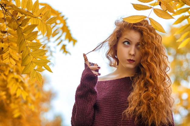 Portrait of red-haired woman with yellow leaves