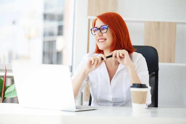 Portrait redhaired beautiful woman working in the office