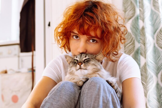 Portrait redhaired curly teenage girl with favorite fluffy domestic cat