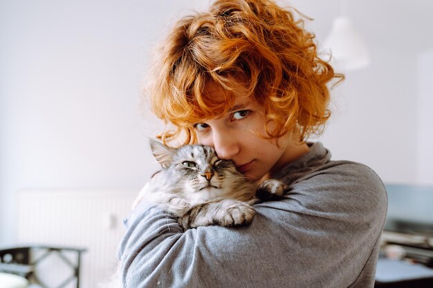 Portrait redhaired curly young woman with beloved fluffy domestic cat