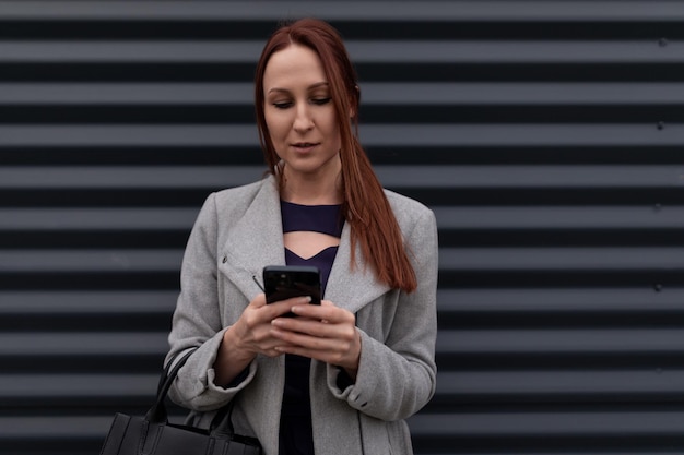 Portrait of a redhaired fortyyearold businesswoman against a gray wall