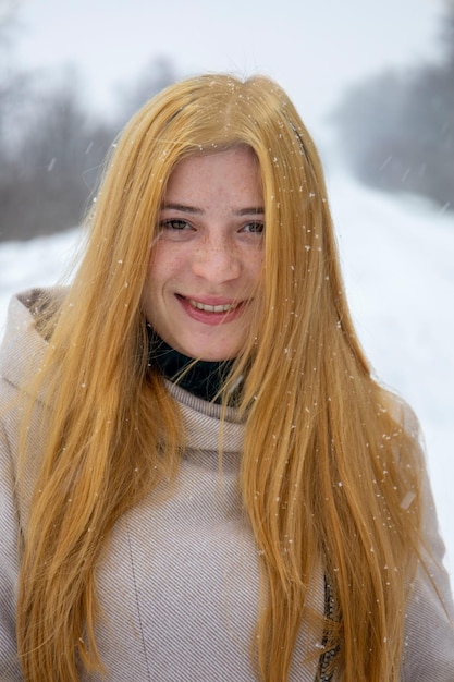 Portrait of a redhaired girl with freckles on her face With blurred snow background