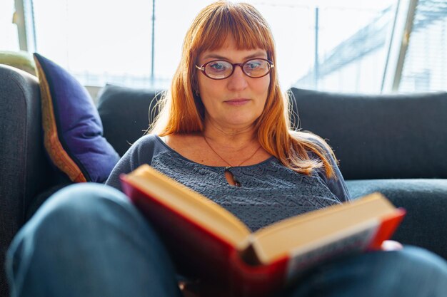 Portrait redhaired woman reading novel book