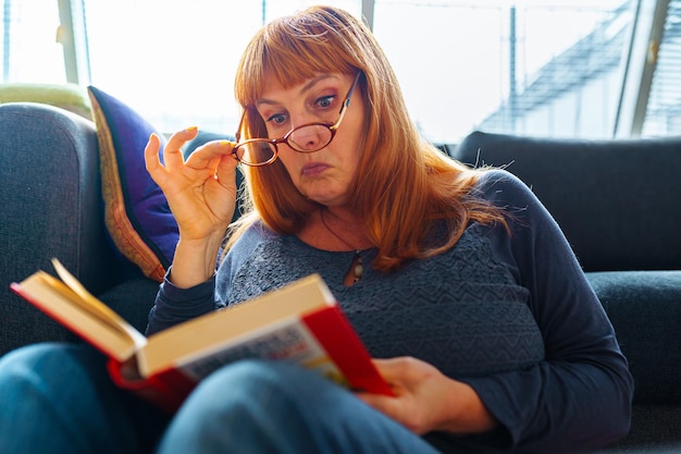 Portrait redhaired woman reading novel book