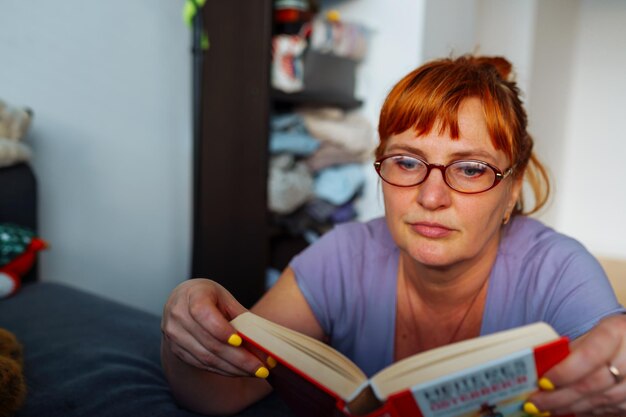 Portrait redhaired woman reading novel book