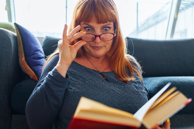 Portrait redhaired woman reading novel book