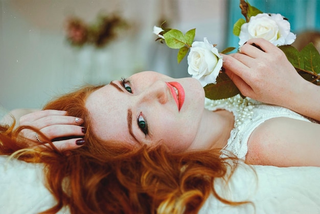 Portrait of redhead girl, young woman in nightie lies in the morning in bed after waking up. Relax