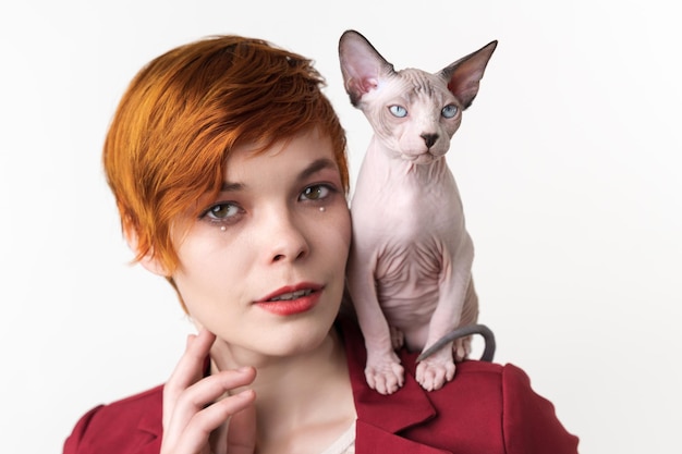 Portrait of redhead young woman with short hair dressed in red jacket and cat sitting on shoulder