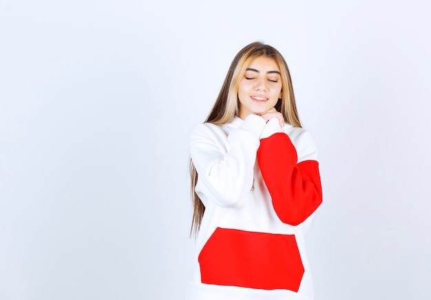 Portrait of a relaxed woman in warm hoodie standing with closed eyes 