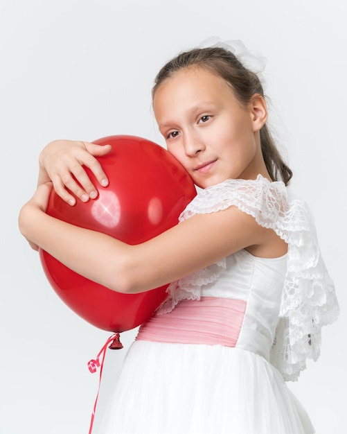 Portrait of romantic girl hugging red balloon and mysteriously looking away on white background