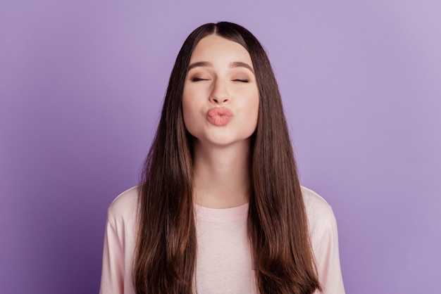 Portrait of romantic woman close eyes blow air kiss isolated on violet background