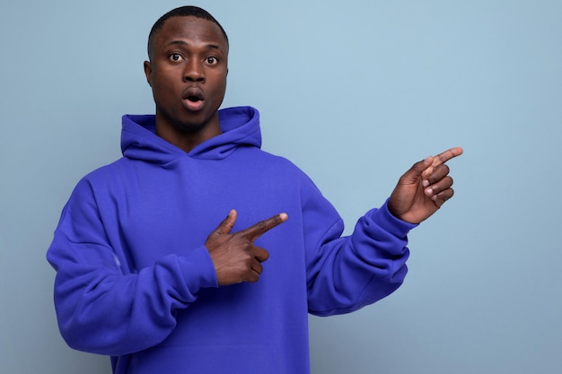 Portrait of s darkskinned african man in hoodie pointing with index finger at idea on studio