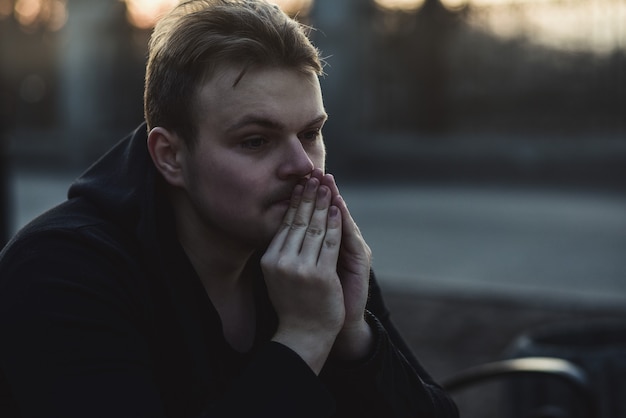 Portrait of a sad and depressed man sitting alone at street