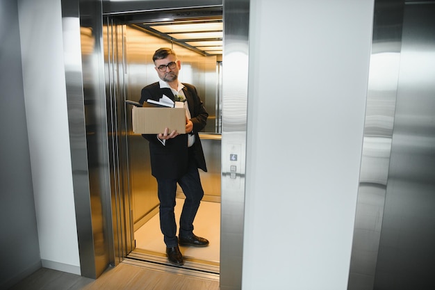 Portrait of sad dismissed senior old business man worker taking his office supplies in the box Pensioner mature retire from work carry staff back home Lifestyle business retirement quit job concept