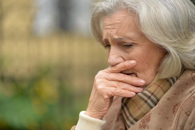 Portrait of a sad elderly woman in autumn park