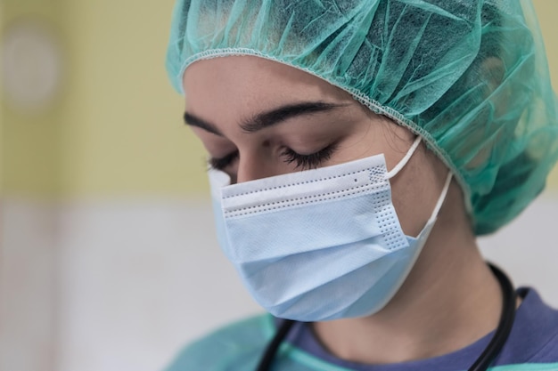 Portrait of sad and overwhelmed doctor wearing protective face mask looking exhausted depressed and