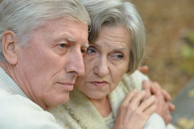 Portrait of a sad senior couple in autumn park