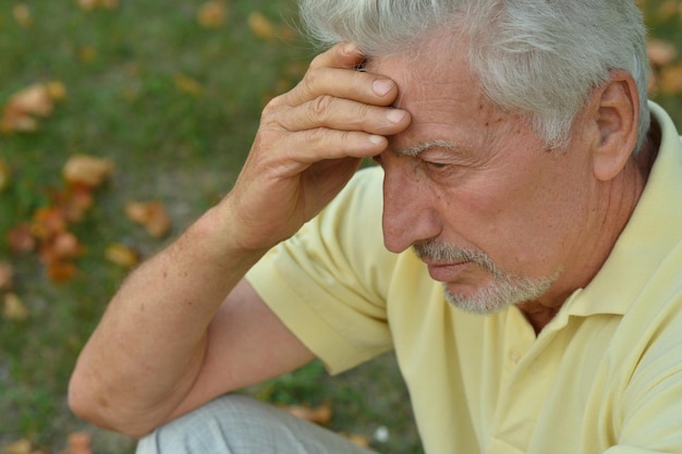 Portrait of sad senior man in green park