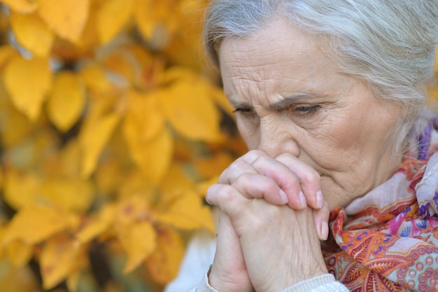 Portrait of a sad senior woman in autumn park