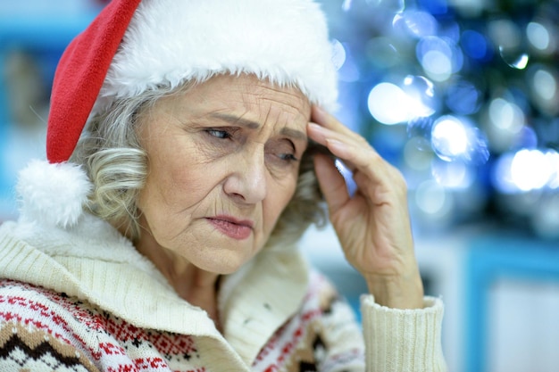 Portrait of sad senior woman in Santa hat