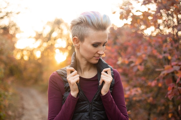 Portrait of sad woman in autumn forest background with golden and red trees