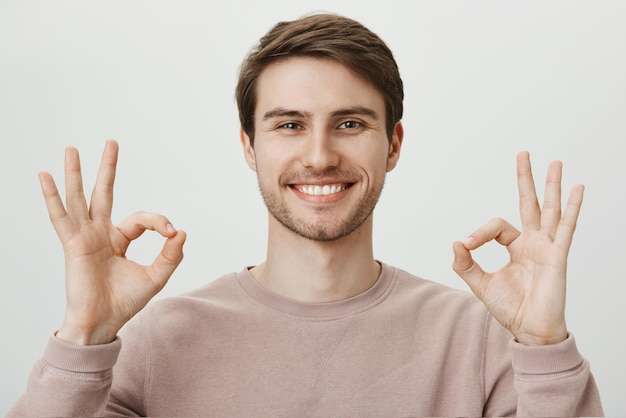 Portrait of satisfied goodlooking mature caucasian guy with bristle showing okay gesture