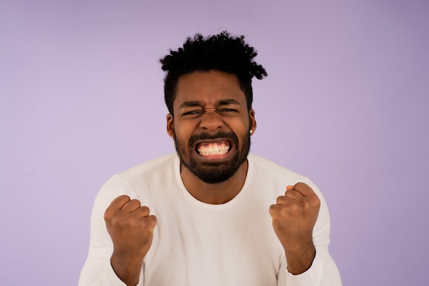 Portrait of a satisfied young man celebrating success while standing against isolated background. Success concept.