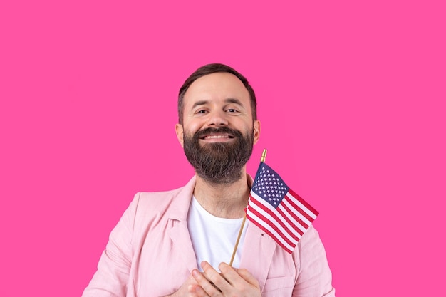 Portrait of a satisfied young man with a beard with an American flag on a red studio background Great US patriot and defender of freedom