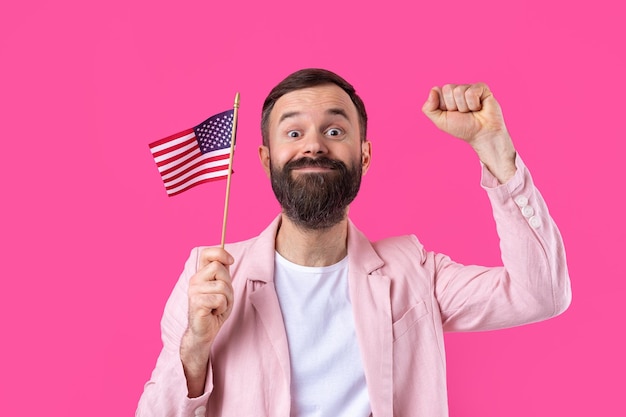 Photo portrait of a satisfied young man with a beard with an american flag on a red studio background great us patriot and defender of freedom