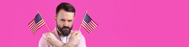 Portrait of a satisfied young man with a beard with an American flag on a red studio background Great US patriot and defender of freedom