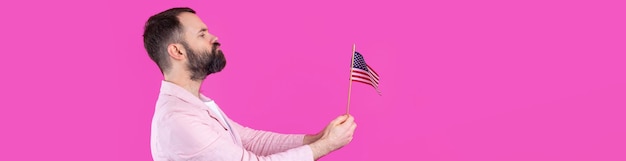 Photo portrait of a satisfied young man with a beard with an american flag on a red studio background great us patriot and defender of freedom