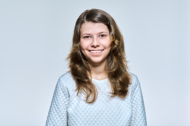 Portrait of schoolgirl 11 12 years old girl looking at camera on light studio background