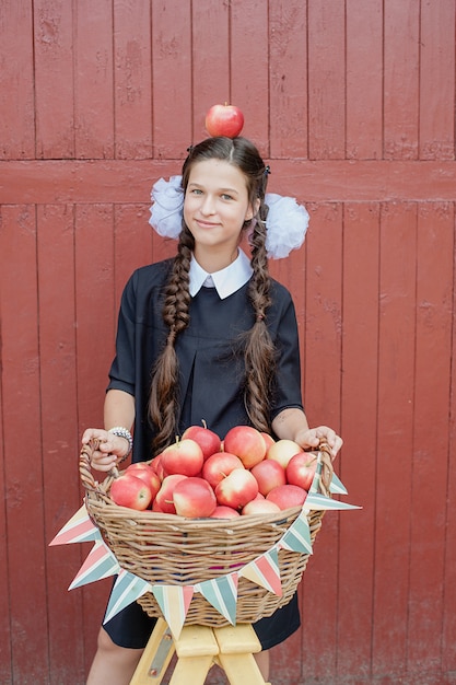 Portrait of a schoolgirl standing with apple on head